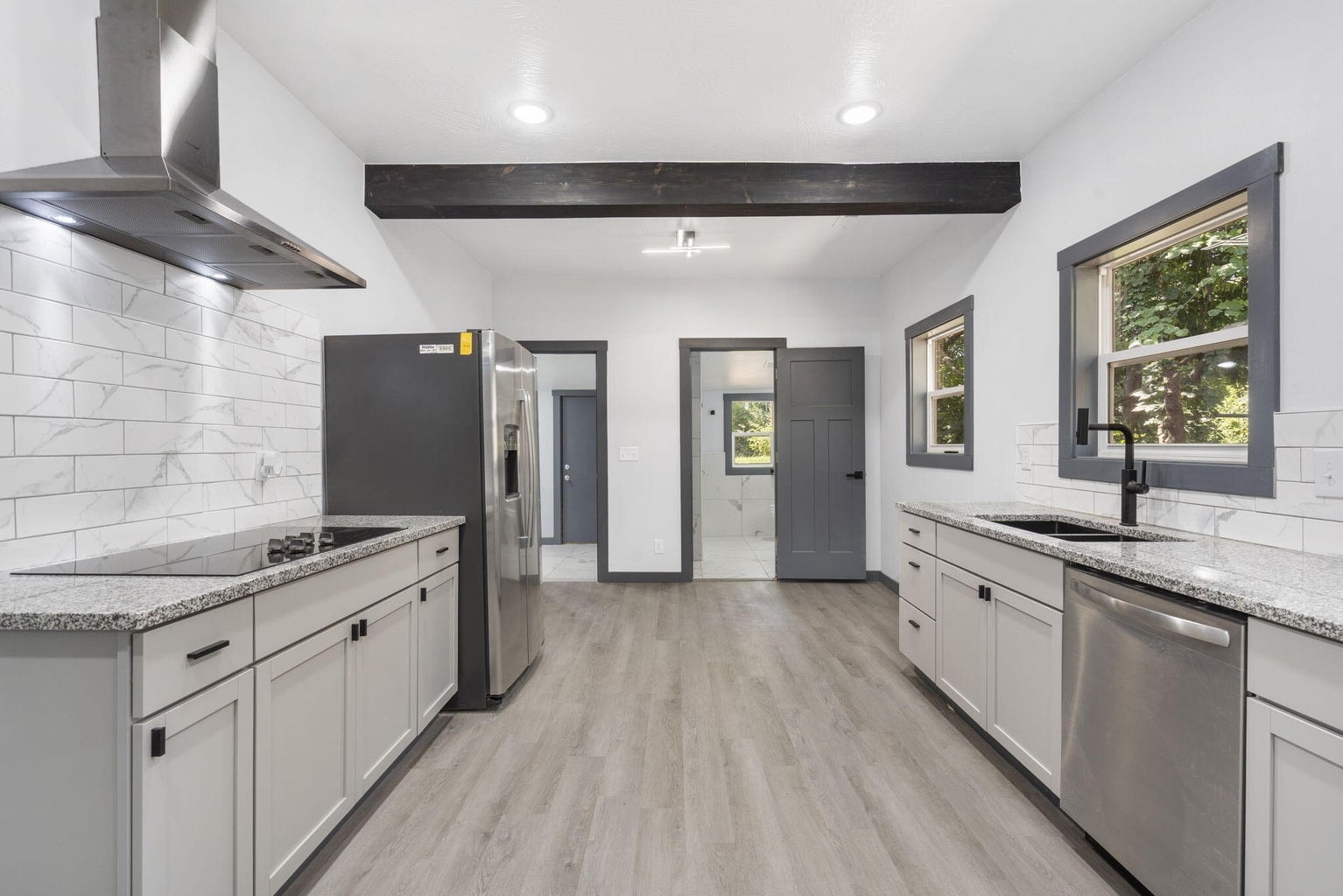 Completed modern kitchen renovation with white cabinetry and stainless steel appliances